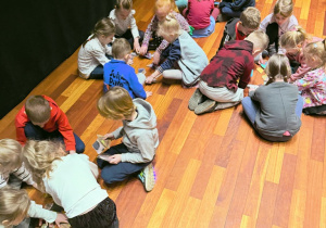 Dzieci siedzą na podłodze i układją puzzle