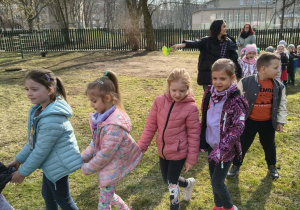 Dzieci podczas spaceru w korowodzie po ogrodzie przedszkolnym