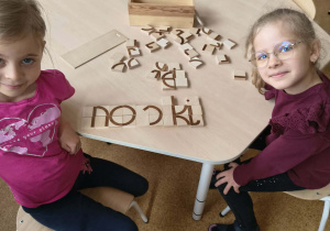 Dziewczynki prezentują ułożony z klocków wyraz "noski"