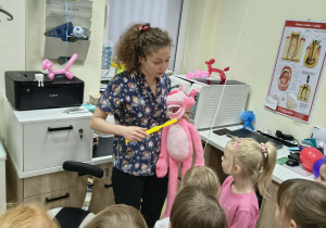 Pani dentystka, wykorzystując maskotkę Różowej Pantery, pokazuje dzieciom, jak prawidłowo myć zęby