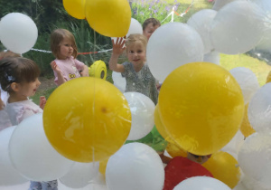 Dzieci w kuli z balonami w ogrodzie