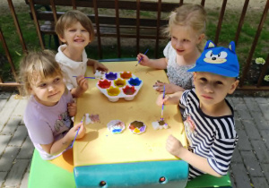 Dzieci malujące na tarasie przy plastikowych stolikach