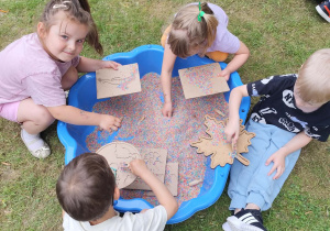 Dzieci podczas zabaw sensorycznych w ogrodzie przedszkolnym