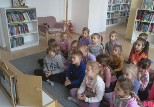 Dzieci słuchają i oglądają ilustracje do opowiadania Teatrzyku Kamishbai "Przytul mnie"