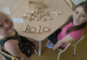 Dziewczynki prezentują ułożony z klocków wyraz "koło"