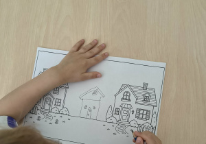 Chłopiec projektuje na kartonie dom pasujący do innych domów
