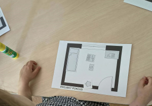 Dziewczynka projektuje na kartonie ustawienie mebli w pokoju dziecięcym