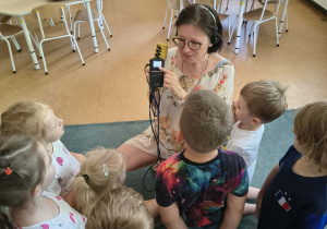 Pani prezentuje dzieciom akcesoria dziennikarza reportera