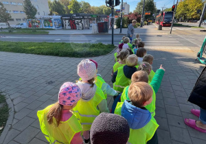 Dzieci przed przejściem dla pieszych czekają na zielone światło, by móc przejść przez jezdnię