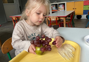 Dziewczynka podczas tworzenia jeżyka z owoców