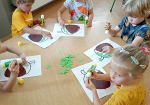 Dzieci wyklejają żołędzie papierem kolorowym