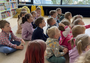 Dzieci na dywanie słuchają czytanej opowieści.