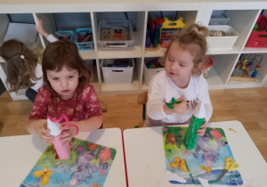 Sala przedszkolna,. Dwie dziewczynki siedzą przy stoliku i manipulują drucikami kreatywnymi.