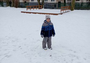 Chłopiec na tle zaśnieżonego ogrodu przedszkolnego