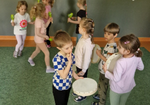dzieci chodząc po kole jednoczesnie grają na marakasach i bębenkach